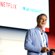 Netflix co-CEO Reed Hastings stands with a tablet in front of a screen reading Netflix and Mediaset.
